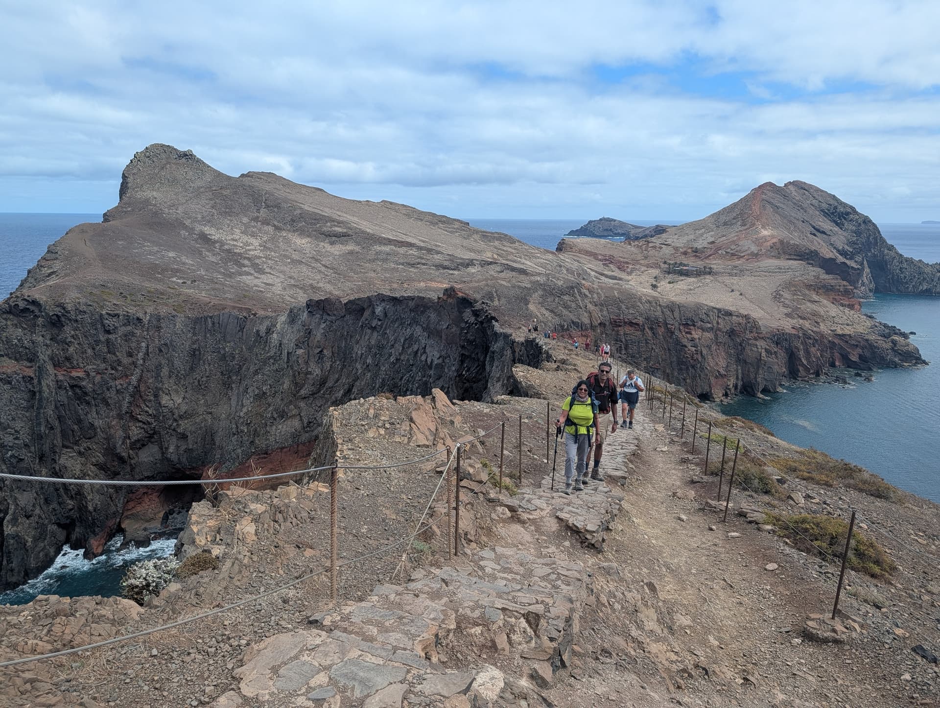 Hikers walking on rocky ridge path along coastal headland with ocean views