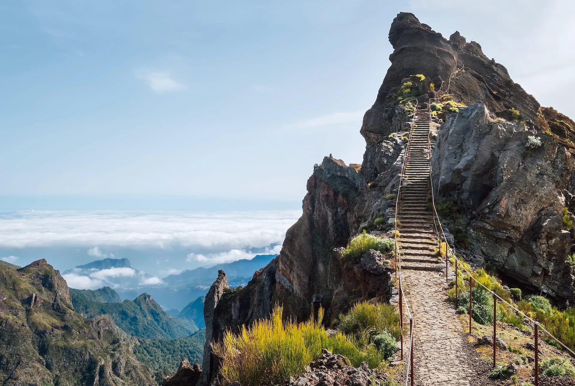 Stone stairs ascending steep rocky peak above clouds at Pico Ruivo, Madeira.